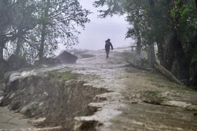 <p>A man walks on a damaged embankment along the Sonatola river during heavy rainfall in Patuakhali </p>
