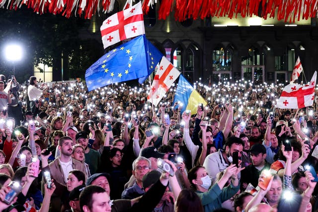 <p>People hold smartphones with flashlights as they protest the ‘foreign influence’ law outside the parliament building in Tbilisi</p>