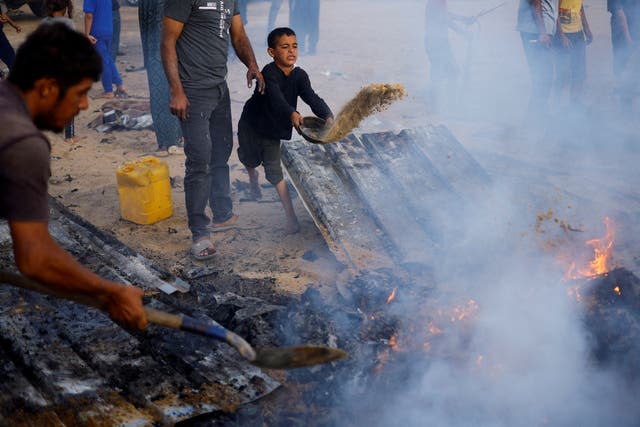 <p>Palestinians put out a fire at the site of an Israeli airstrike on an area designated for displaced people in Rafah </p>