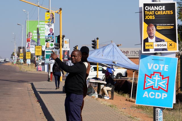 <p>A man waits for a  taxi along a street lined with election posters in the Hammanskraal township, Pretoria</p>