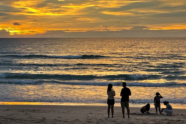 <p>Tourists stand on Bang Tao Beach in Phuket, southern Thailand</p>